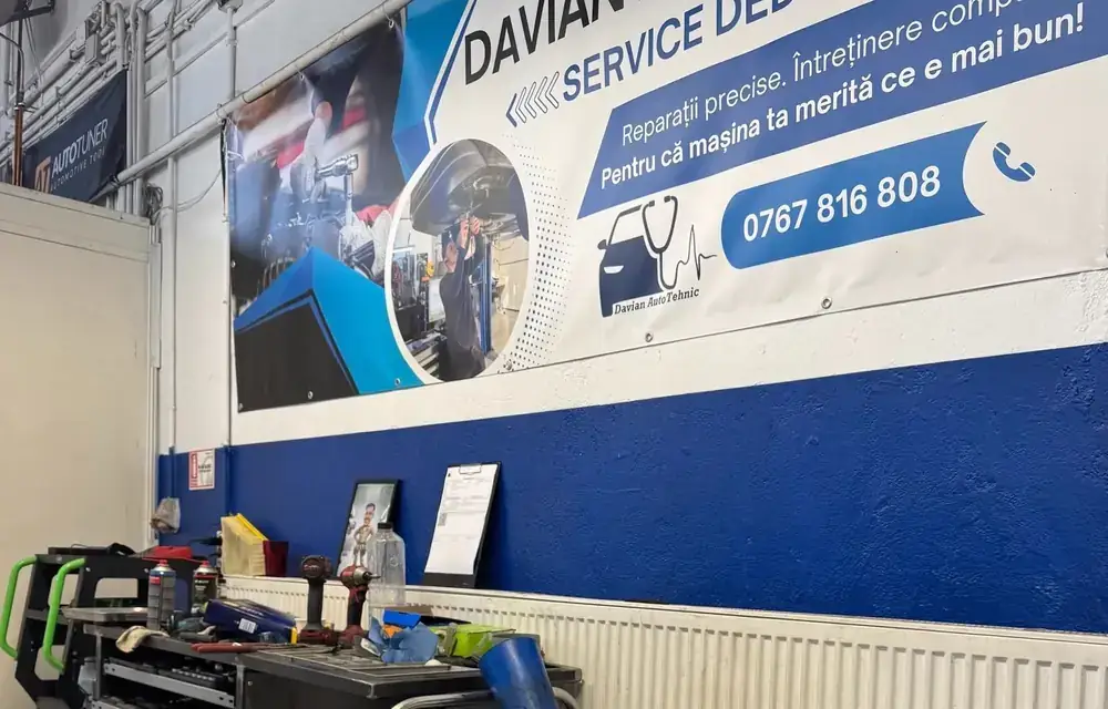 Bannerul Davian AutoTehnic, service dedicat VAG, pe peretele atelierului, lângă un chiulasă pregătită pentru montaj